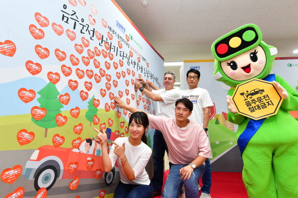 ‘음주운전 안하기 다짐 서약’에 참여한 새내기 운전자들이 고동우 오비맥주 대표(뒷줄 왼쪽), 장유택 오비맥주 정책홍보 부사장(뒷줄 오른쪽)과 함께 서약 스티커를 안전운행 도로 서약판에 부착하고 있다. 사진=오비맥주 제공.