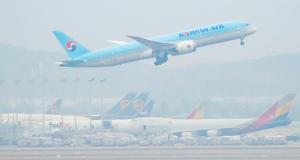 인천국제공항 주기장에 세워진 아시아나항공 여객기 위로 대한항공 여객기가 이륙하고 있다. 사진=연합뉴스