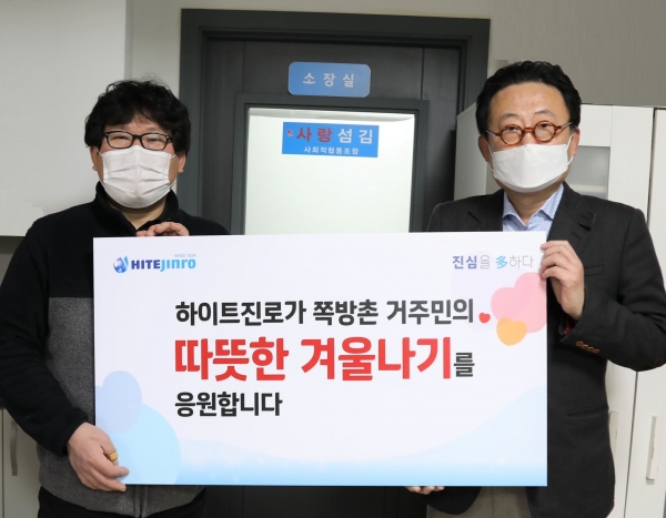 25일 류준형 하이트진로 상무(오른쪽)은 김형옥 영등포 쪽방상담소 소장을 만나 쪽방촌 거주민을 위한 떡과 핫팩을 전달했다. 사진=하이트진로 제공.