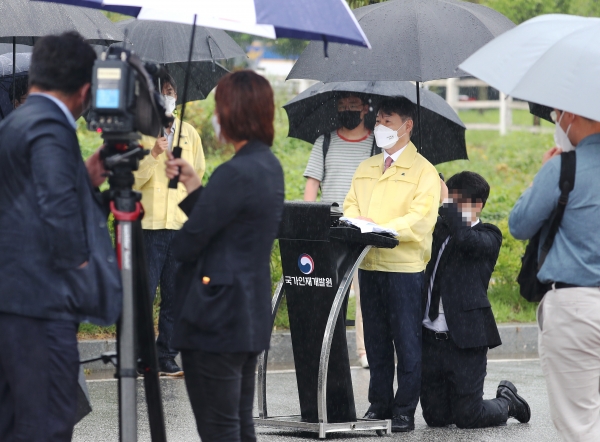 27일 강성국 법무부 차관이 브리핑하는 도중 관계자가 뒤쪽에서 무릎을 꿇고 우산을 받쳐주고 있다. 사진=연합뉴스 제공